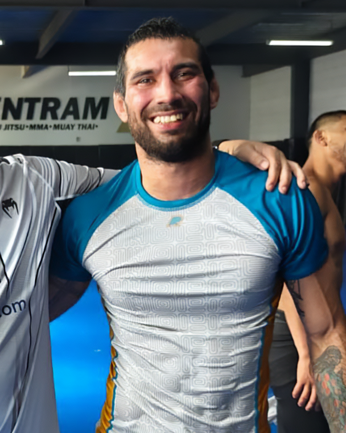Male jiu-jitsu trainer smiling at gym after tragic freak accident involving paralyzing sparring incident.