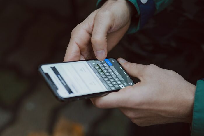 Person holding smartphone typing on keyboard, illustrating subtle signs that they're cheating once noticed.