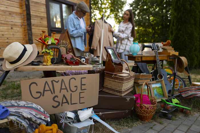 Two women browsing items at a garage sale, highlighting gifting broken stuff and green living concerns.