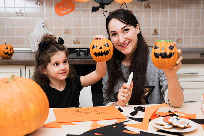Woman and child carving Halloween pumpkins at home, capturing a holiday moment amidst family tensions.
