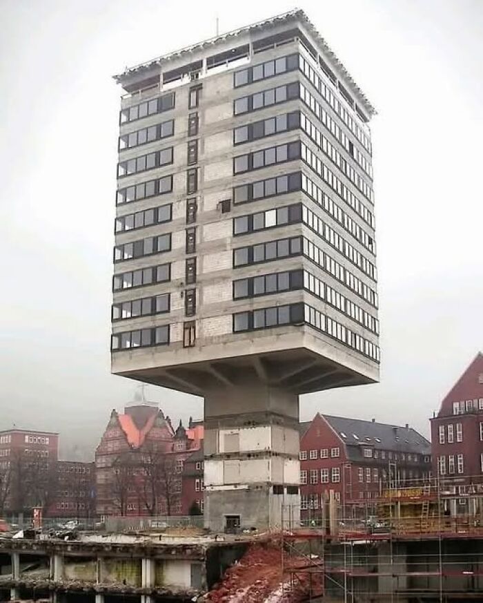 Unesthetic building with a blocky design elevated on a narrow concrete base in an urban area showing ugly modern architecture.