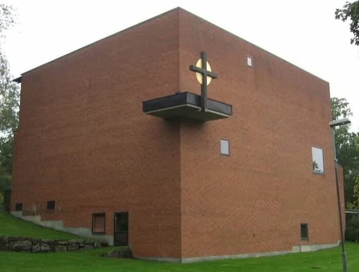 Large ugly brick building with minimal windows and a protruding cross, exemplifying unesthetic modern architecture.