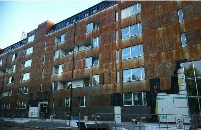 Rusty and unesthetic modern building facade with multiple windows, showcasing ugly architecture that harms urban aesthetics.
