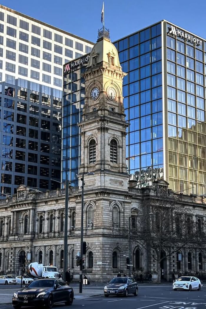 Historic clock tower building in front of modern glass Marriott skyscrapers, illustrating ugly and unesthetic buildings in architecture.