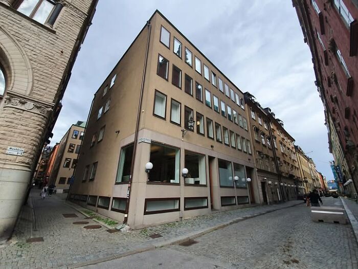Beige modern architecture building on a narrow cobblestone street with dull, unesthetic design elements.
