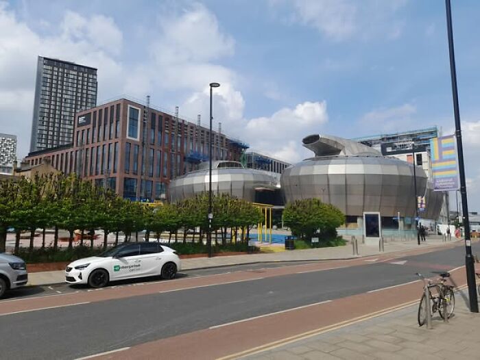 Modern architecture featuring unusual, unesthetic, and ugly buildings under a partly cloudy sky in an urban setting.