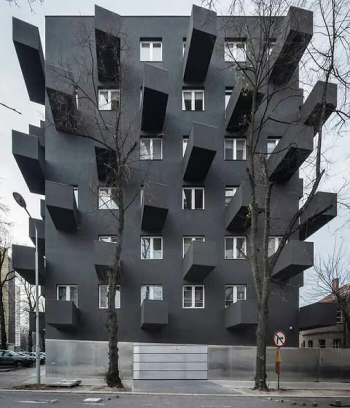 Dark gray modern apartment building with protruding box balconies, illustrating ugly unesthetic and depressing buildings in architecture.