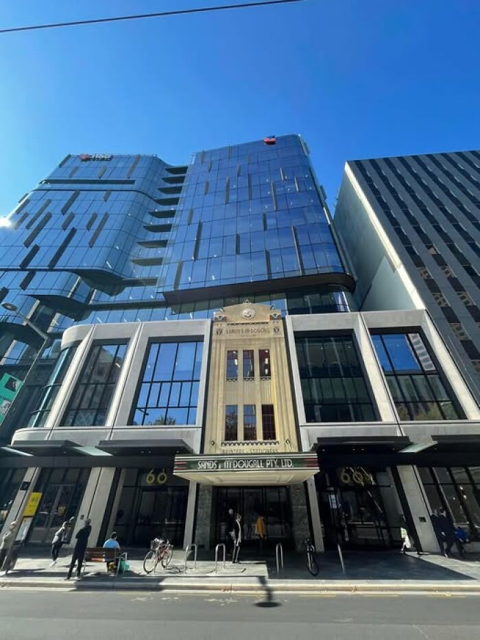 Modern architecture building with glass facade and unesthetic design under clear blue sky in urban street view.