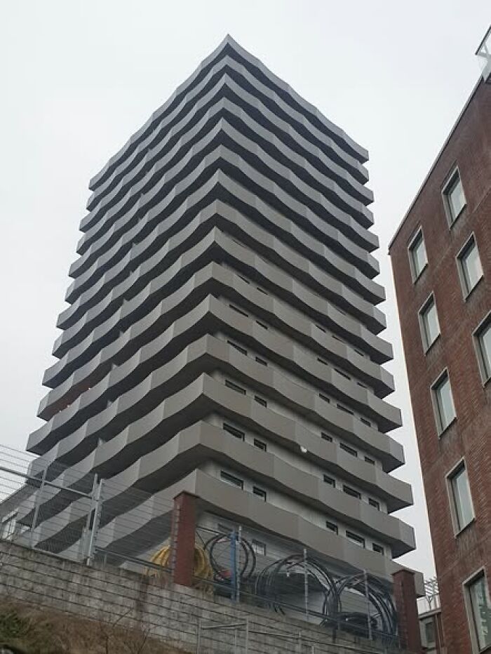 Wavy facade on a high-rise building with a gray overcast sky, showcasing unesthetic and ugly modern architecture design.