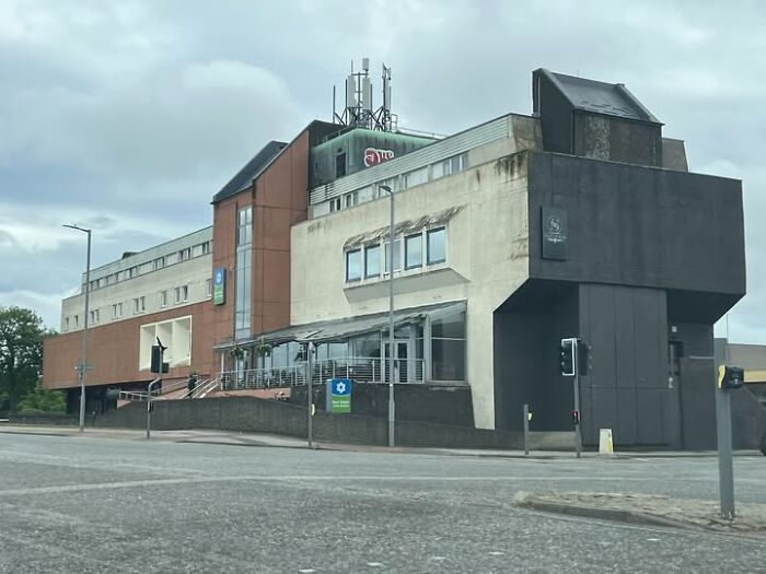 Brutalist modern architecture building with unesthetic and ugly design elements in an urban setting on a cloudy day.