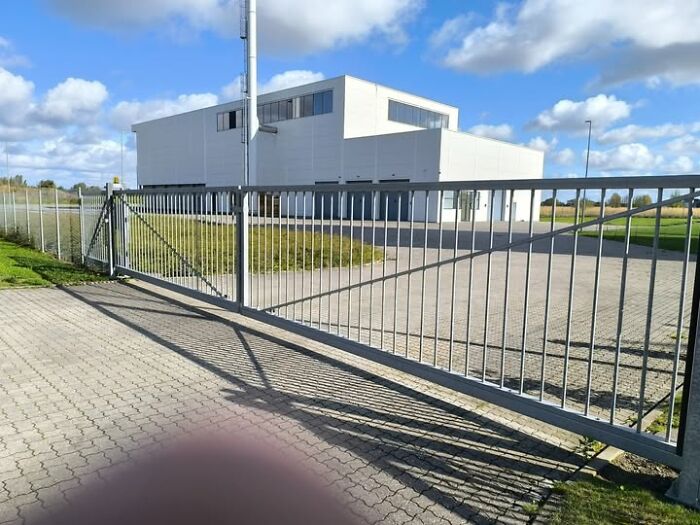 Minimalist modern building with plain white facade behind a metal gate, illustrating ugly and unesthetic buildings in architecture.