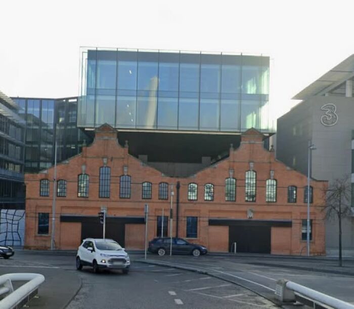 Modern architecture with ugly and unesthetic design combining old brick building and glass structure above.