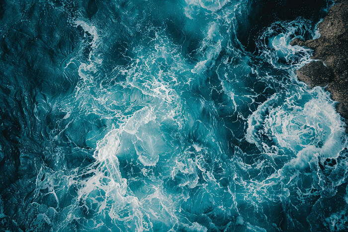 Turbulent ocean waves crashing against rocky shore, illustrating dynamic changes and upcoming events to pay attention to online.