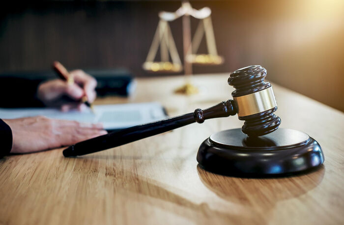Gavel on a wooden desk with scales of justice in background, highlighting key events in an online thread.