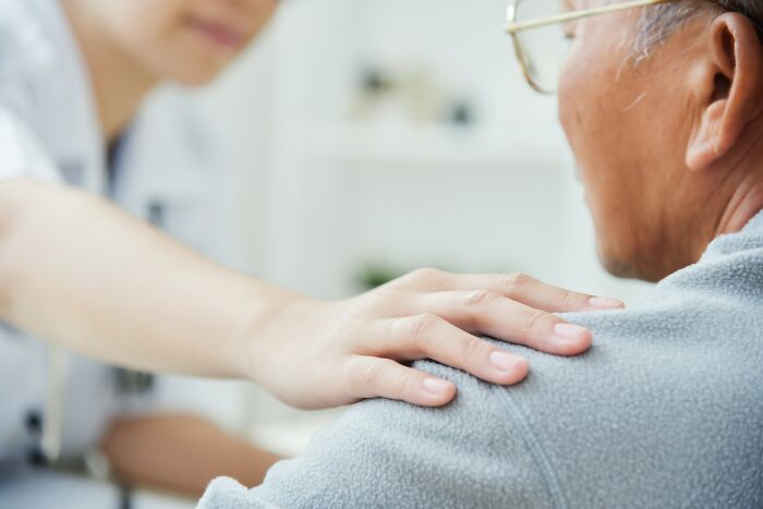 Caregiver gently placing hand on elderly man’s shoulder, illustrating toxic relationship traits and emotional support challenges.