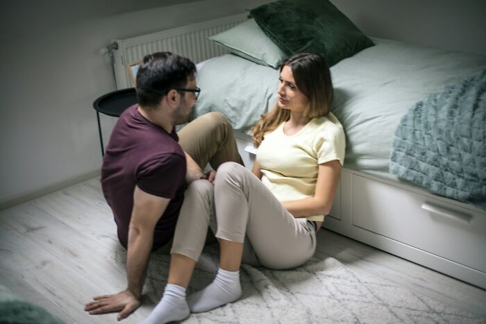 Couple having a serious conversation on the floor, illustrating harsh truths about marriage and relationship challenges.