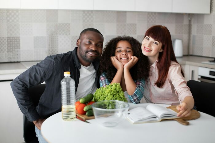 Happy family in kitchen smiling together around fresh vegetables, capturing moments people wanted to say something funny to loved ones.
