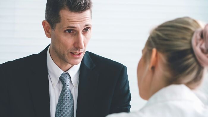 Man in a suit discussing toxic relationship traits with a woman in a professional office setting.