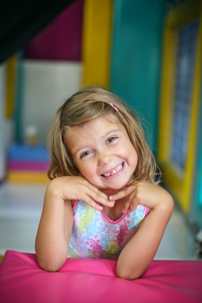 Smiling young girl posing indoors, capturing funny and serious moments parents realize they are raising monsters.