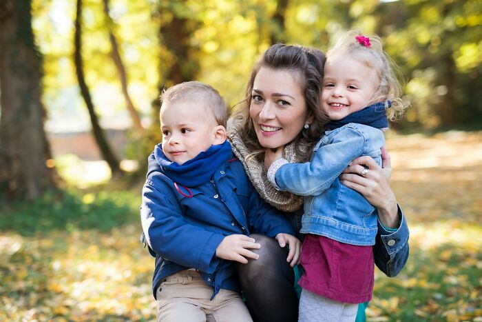 Mother hugging her two children outdoors in autumn, illustrating family dynamics where the golden child isn't always golden.
