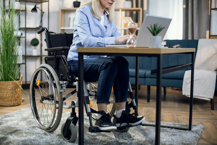 Woman in a wheelchair working on a laptop at home, highlighting people sharing mysterious medical issues and diagnoses.