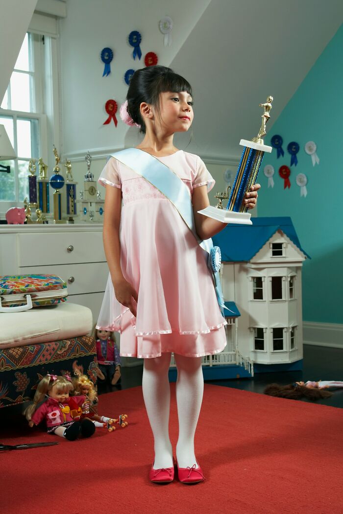 Young girl in a pink dress holding a trophy, highlighting common parenting mistakes in raising kids successfully.