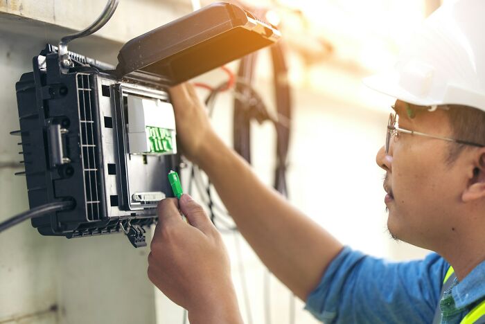 Worker in safety helmet handling electrical equipment, illustrating workers share unprofessional things done in the workplace.