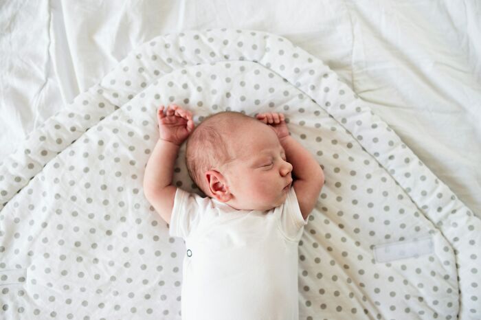 Newborn baby sleeping peacefully on a polka dot blanket, illustrating stories of families with golden child challenges.