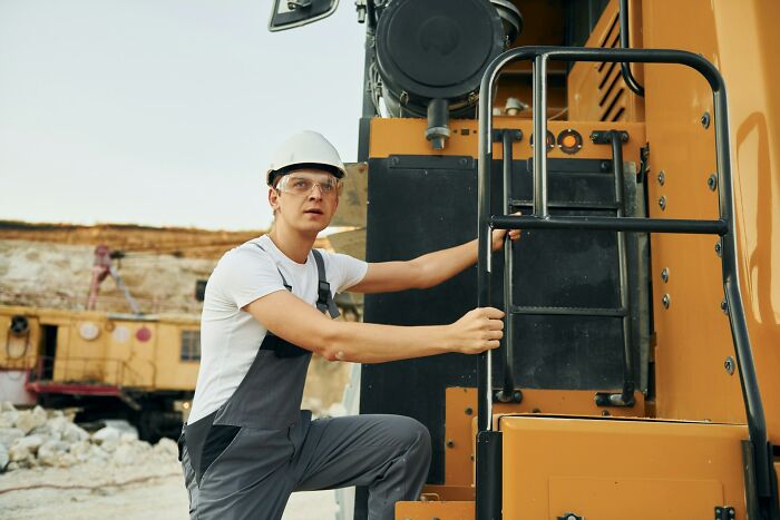 Construction worker wearing safety gear operating heavy machinery, illustrating work secrets about trades like plumber and barista.
