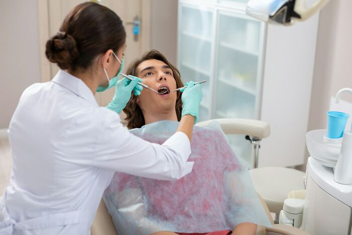 Dentist examining patient’s mouth wearing gloves and mask, illustrating wildest patient horror stories dentists recall.