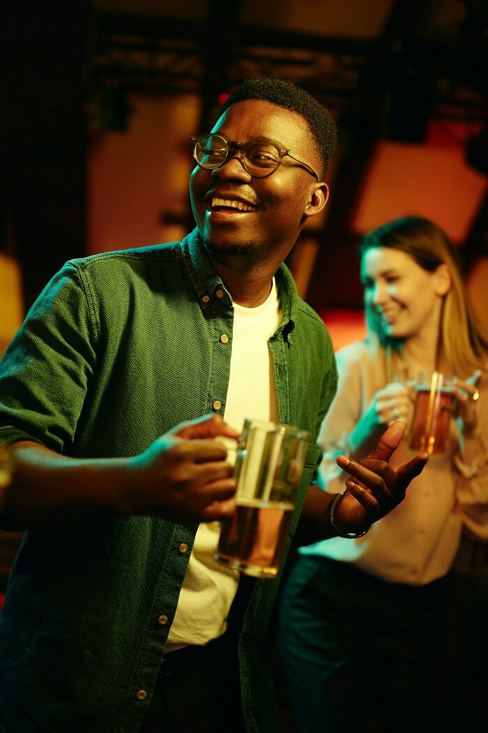 Young man and woman enjoying drinks at a party, representing love and friendship moments before trust is broken.