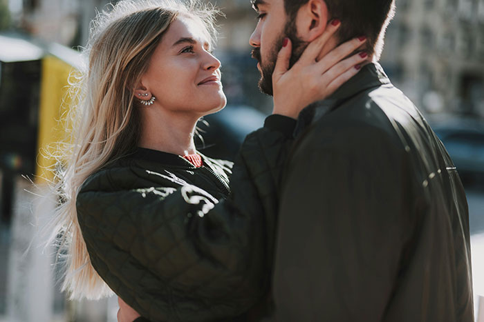 A toxic girlfriend holding her boyfriend's face outdoors, with tension reflecting a reluctant choice between bestie and boyfriend.