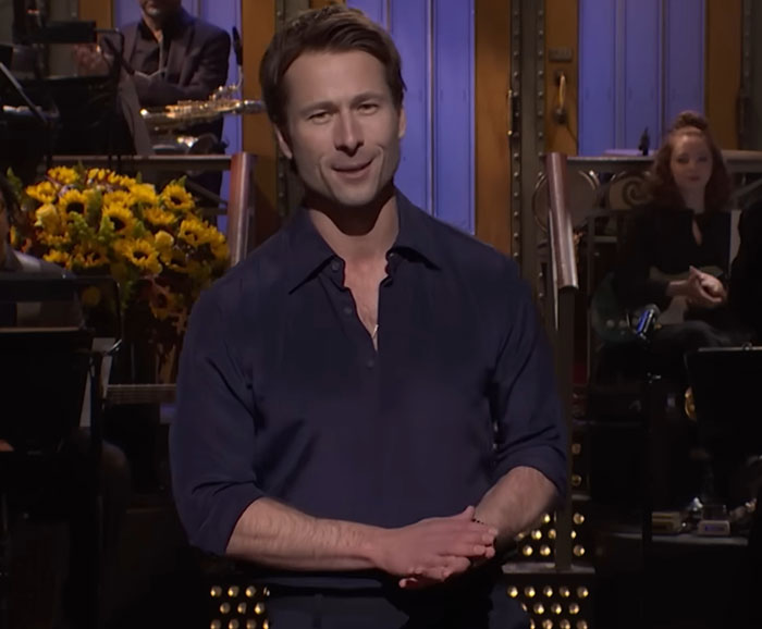 Glenn Powell on stage at SNL, speaking emotionally about flying UPS driver and sharing his dream story.