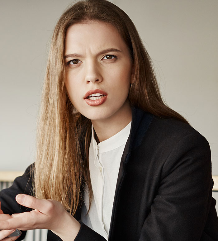 Young woman looking frustrated and upset while discussing parents demanding she give up career opportunity to golden-child sister
