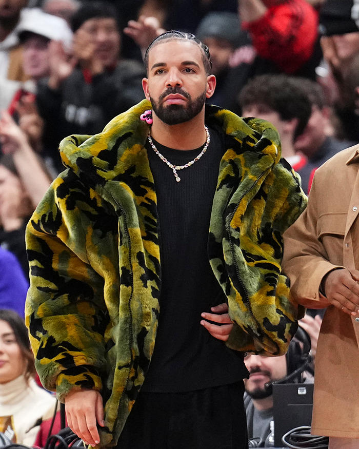Drake wearing a green camouflage fur coat and necklace at a crowded event, revealing party details that ended everything.