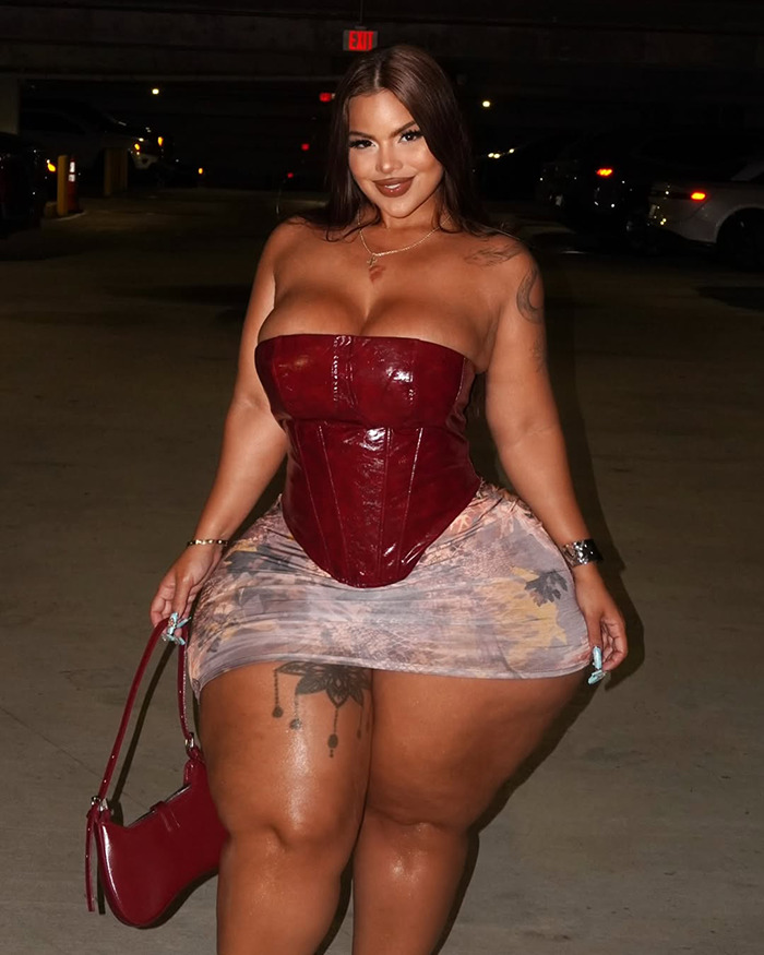 Curvy woman in a red corset and patterned skirt posing confidently at night, related to Drake party revelation.