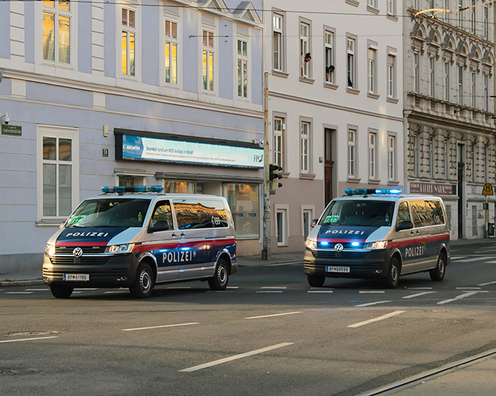 Two police vans with flashing lights parked on a city street during an investigation related to influencer vanishing.