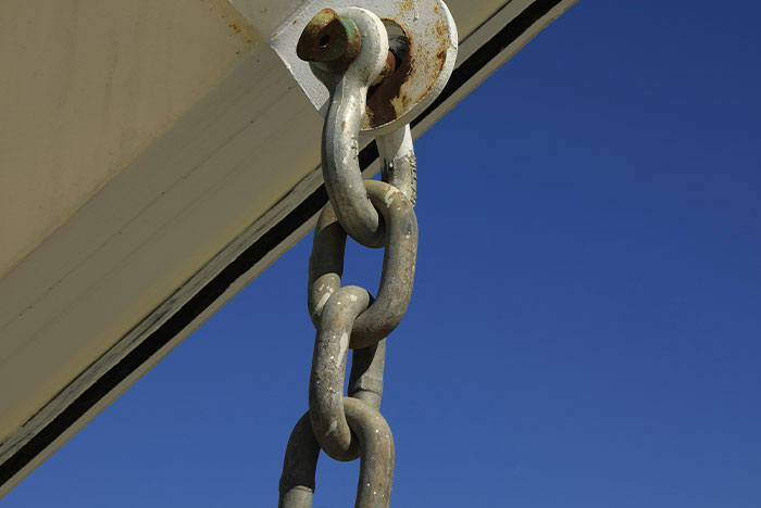 Close-up of a metal chain link holding a structure against a clear blue sky symbolizing strong gut instinct moments.