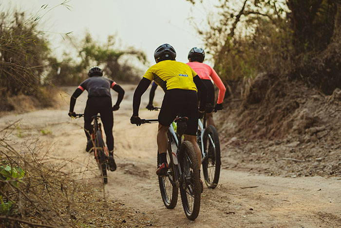 Three cyclists riding on a dirt trail through a forest, capturing moments where their gut instinct was 100% correct.