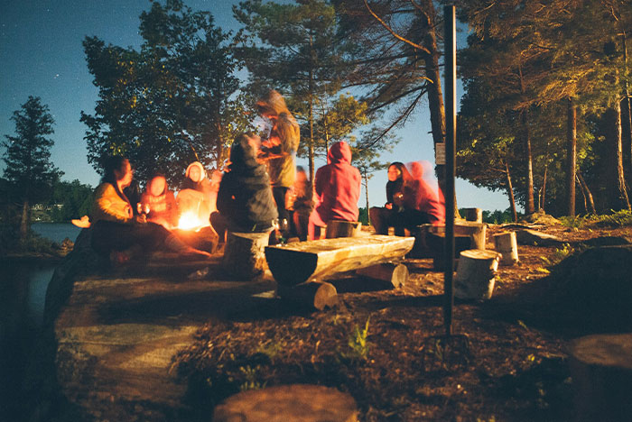 Group of people gathered around a campfire at night in the woods, sharing moments linked to gut instinct being correct.