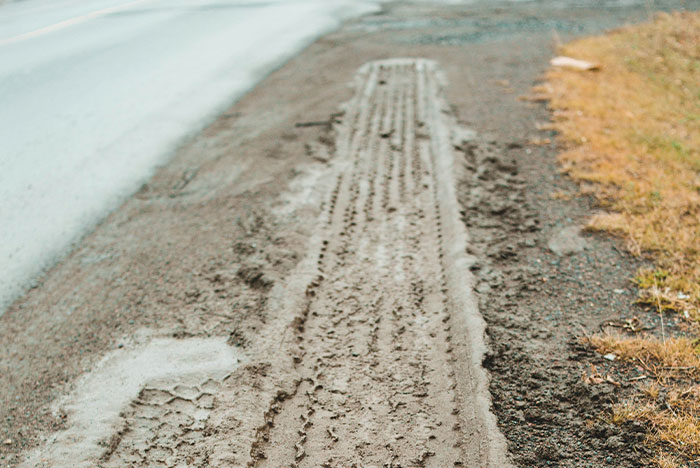 Tire tracks and a footprint on a muddy roadside showing signs people trusted their gut instinct correctly.
