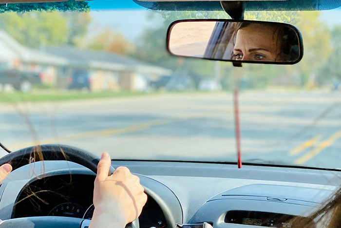 Woman driving a car, focused and alert, trusting her gut instinct while navigating a quiet suburban road.