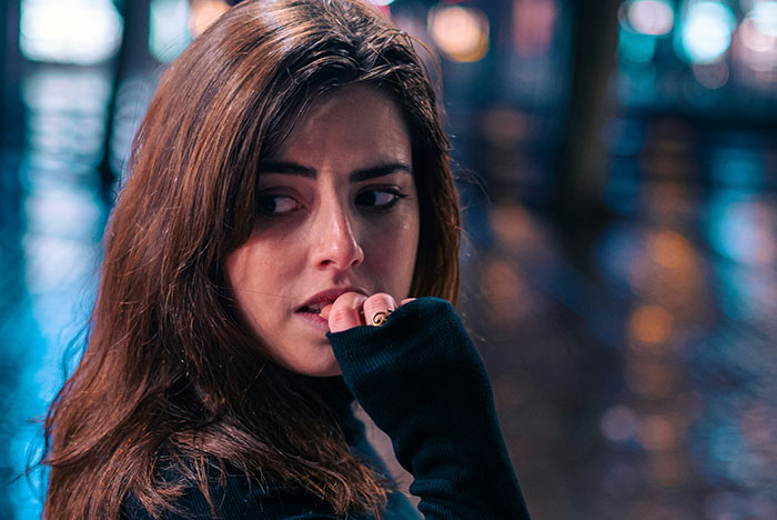 Woman with worried expression in a dark setting, illustrating moments when gut instinct was 100 percent correct.