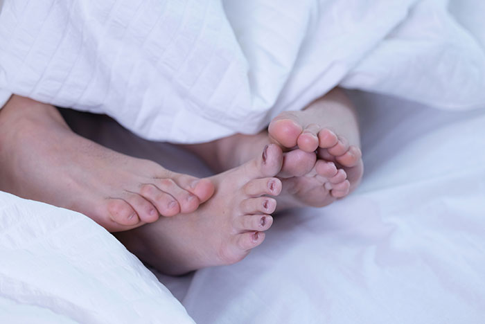 Two pairs of bare feet peeking out from under white bed sheets, illustrating moments gut instinct was correct.