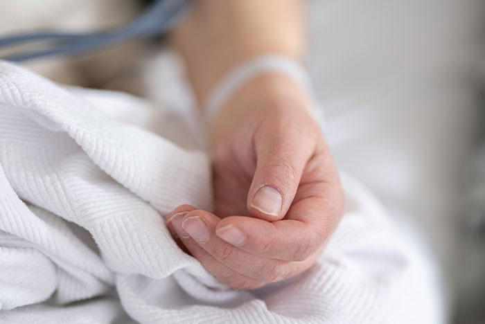 Close-up of a person's hand resting on a white blanket, conveying moments when gut instinct was 100% correct.