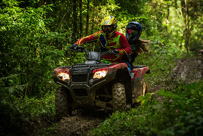 Two people riding a red ATV through a dense green forest, capturing moments when gut instinct was 100% correct