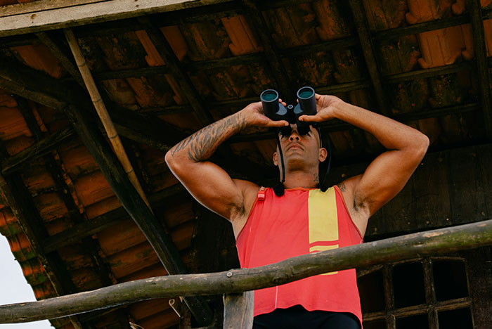 Man in red vest looking through binoculars from wooden balcony, embodying moments when gut instinct was correct