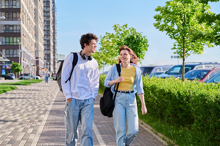 Two young adults walking and smiling on a city sidewalk, capturing a moment of longtime friendship and loyalty test.