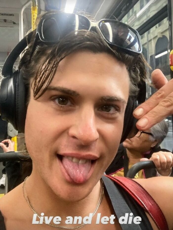 Close-up of a trans woman wearing headphones and sunglasses, expressing a playful mood during her daily commute.