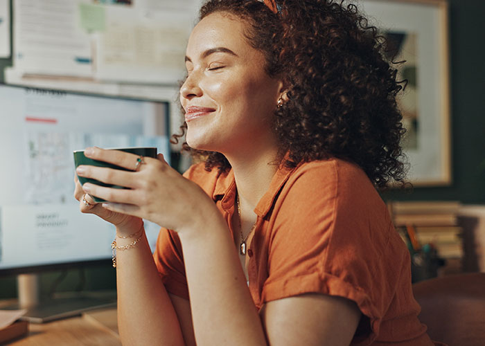 Woman enjoying a moment of wellness holding a cup, exemplifying unusual wellness habits experts swear by.